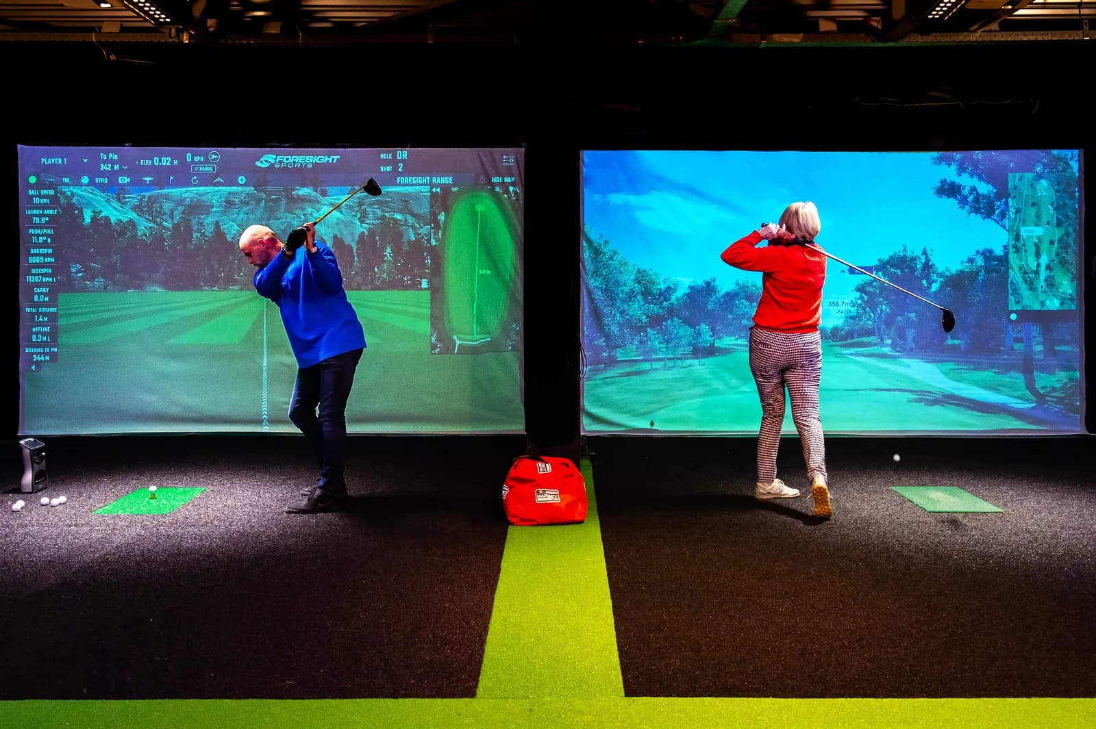 Twee golfers in de simulatorcabines van Indoorgolf Zeeland