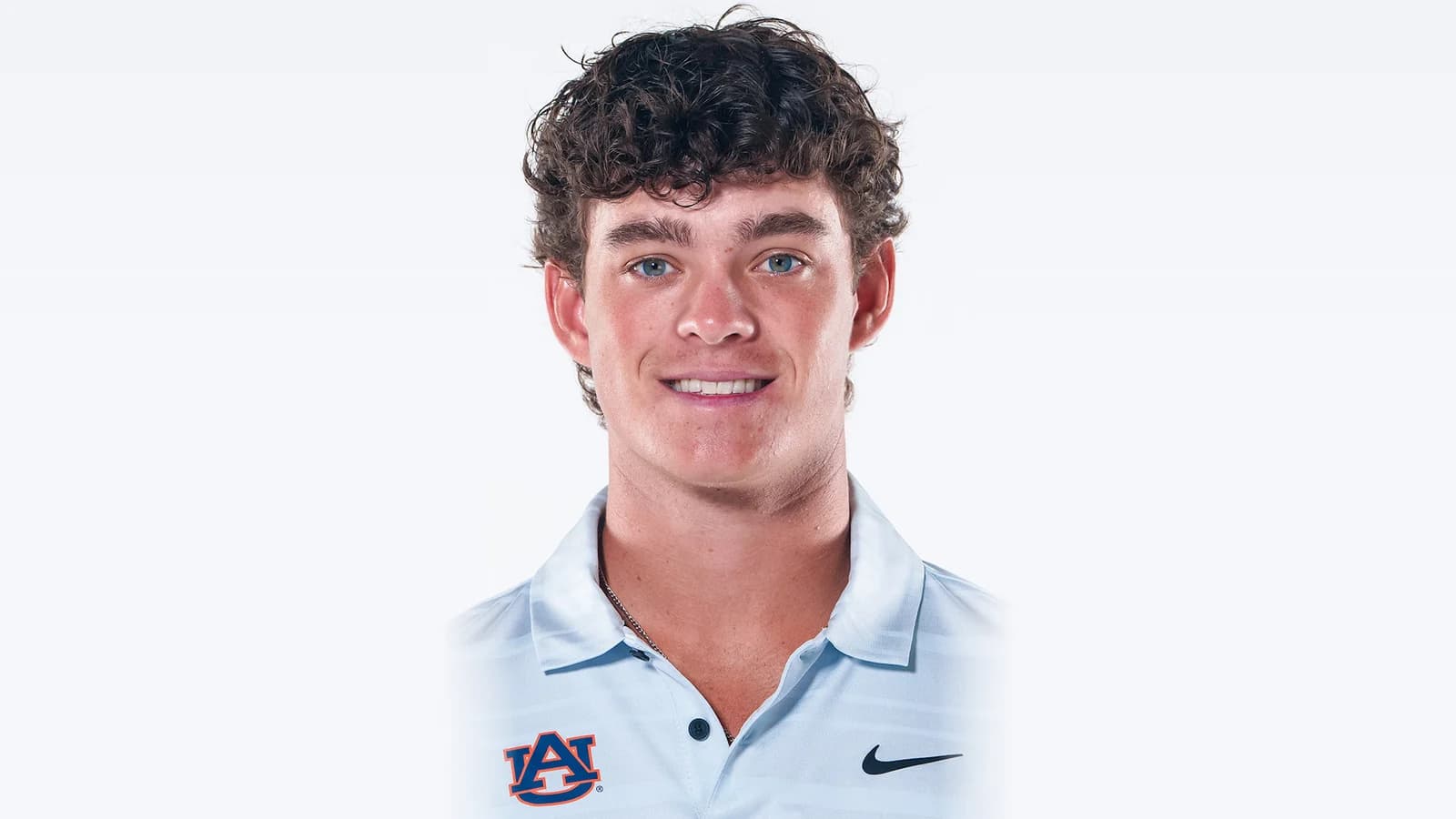 Jackson Koivun lacht in een Auburn-golfpolo voor een lichtgrijze studioachtergrond
